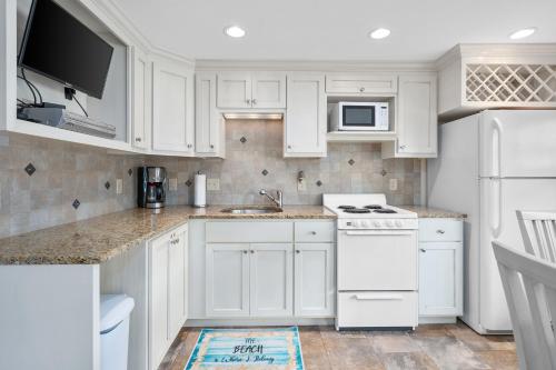 a kitchen with white cabinets and a white stove top oven at Oceanside Condos in Dennis Port