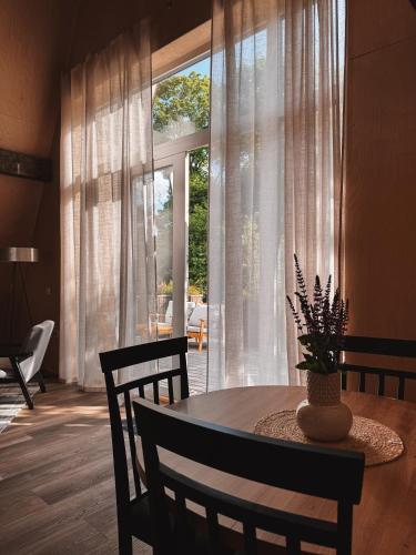 a dining room with a table and a large window at Mulberynas in Stakliškės