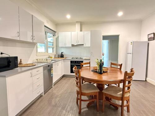 a kitchen with a wooden table and white cabinets at Bendigo Bliss - Cheerful & Spacious Home in Bendigo in Kangaroo Flat