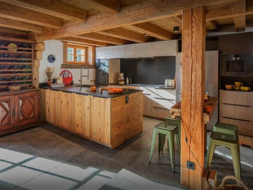 une cuisine avec des placards en bois et des tabourets verts dans l'établissement Chalet Sisar - OVO Network, à La Clusaz