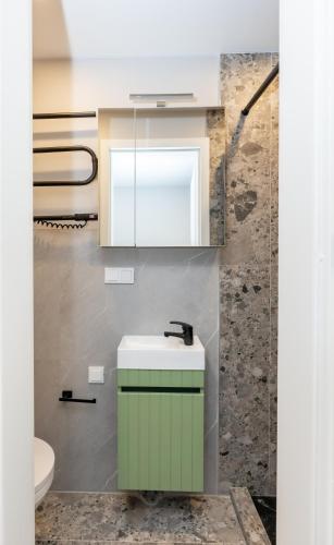 a bathroom with a green sink and a mirror at Miniukas in Kaunas