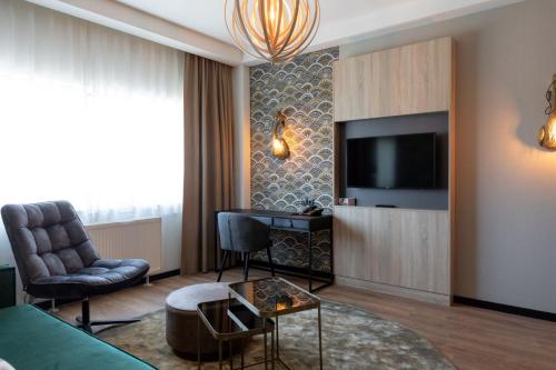 a living room with a television and a couch and a chair at Shanghai Hotel Holland in Delft