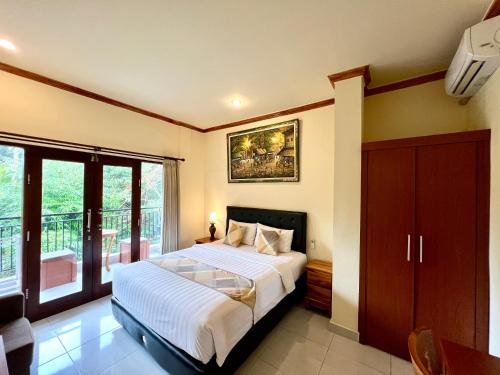 a bedroom with a large bed and a balcony at Guesthouse Gusti Putu Oka in Ubud