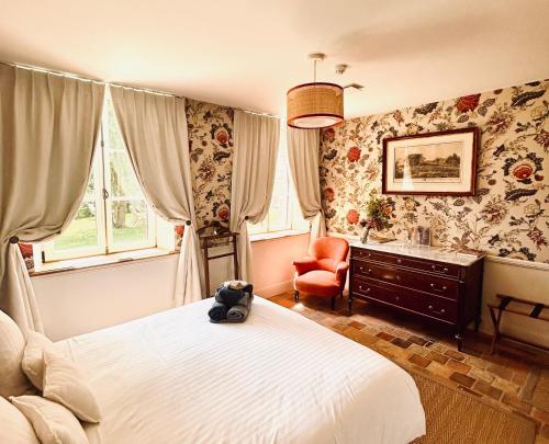 a bedroom with a bed and a chair and windows at Manoir de Daubeuf in Daubeuf-Serville
