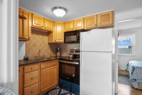 a kitchen with wooden cabinets and a white refrigerator at Oceanside Condos in Dennis Port