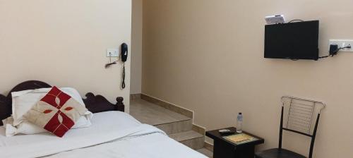 a room with a bed and a television on the wall at Sacred Stay in Guwahati