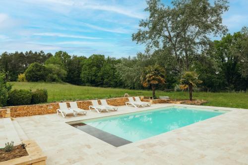 une piscine avec des chaises et un mur en briques dans l'établissement Maison du Noyer, Parc de la Fage, à Journiac