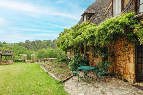 - une table et des chaises dans une cour à côté d'un bâtiment dans l'établissement Maison du Noyer, Parc de la Fage, à Journiac