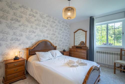 ein Schlafzimmer mit einem Bett mit einer Kommode und einem Spiegel in der Unterkunft Casa da Carballeira in A Estrada