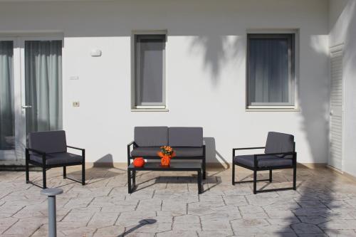 three chairs and a table with flowers on a patio at Dani's residence in Supersano