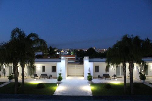 a house with a courtyard with palm trees and lights at Dani's residence in Supersano