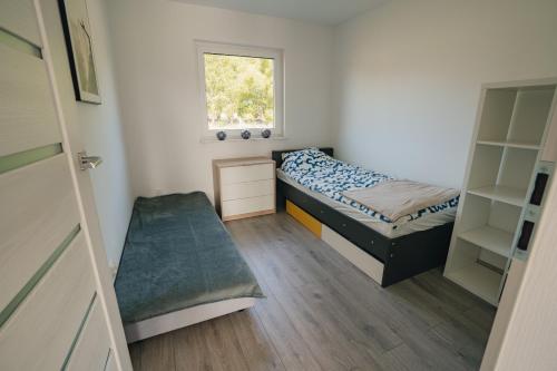 a small bedroom with two beds and a window at Domek wakacyjny Średnia Huta in Warlubie