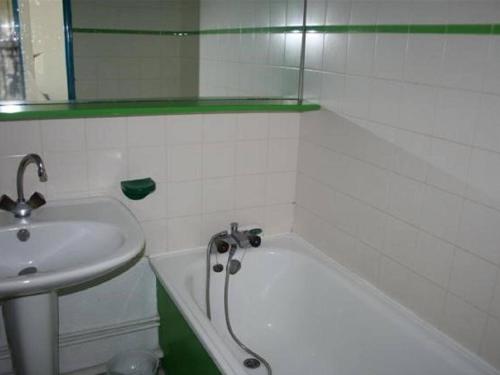 La salle de bains est pourvue d'un lavabo et d'une baignoire à côté d'un miroir. dans l'établissement Appartement 4 pers - Le Barcarès - Piscine, Parkings, Terrains de Sport, Fitness - FR-1-195-25, au Barcarès