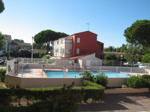 une personne debout dans une piscine avec un bâtiment rouge dans l'établissement T2 rénové avec cabine, piscine, animaux admis, parking à 500m de la plage - FR-1-106-49, à Saint-Cyprien
