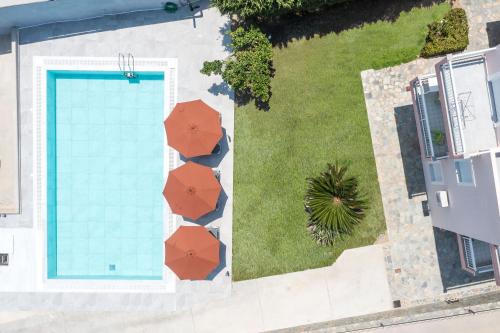 an overhead view of a swimming pool with red umbrellas at Palmtrees Apartments in Afantou