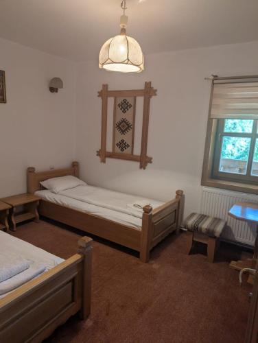 a bedroom with two beds and a table and a window at Vila Bârsana in Bîrsana