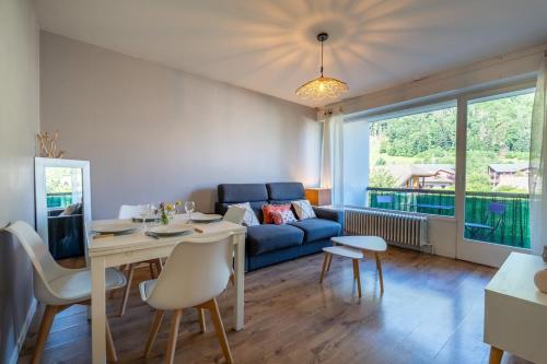 ein Wohnzimmer mit einem Tisch und einem blauen Sofa in der Unterkunft Proche centre Thônes, Apt Cosy entre Lac&Montagnes in Thônes