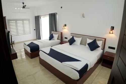 a hotel room with two beds and a television at Teak and Lake Homestay in Thekkady