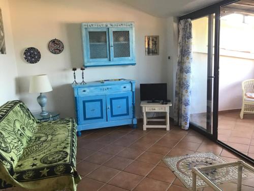 a living room with a blue cabinet and a chair at FABULOUS APARTMENT in COSTA SMERALDA in Cala Bitta