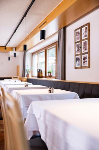 a row of tables in a restaurant with white linens at Hotel Gesser in Sillian