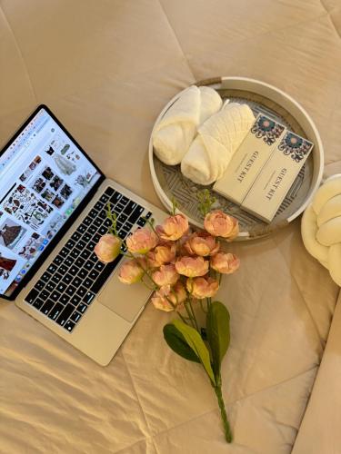 a laptop computer and a bowl of cookies and a plate of flowers at The Cozy Clouds Staycation in Suba