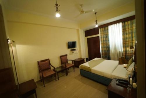 a hotel room with a bed and a table and chairs at Hotel Saket In Prayagraj in Prayagraj