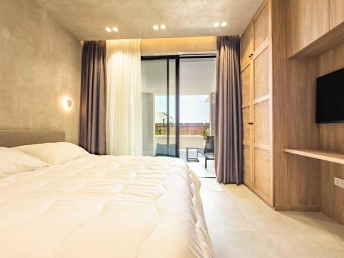 a bedroom with a large white bed and a television at Villa 4 - Drymades - Thymus Residence in Dhërmi