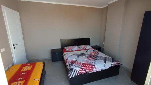 a small bedroom with a bed and a orange table at Maksimilian Apartament in Durrës