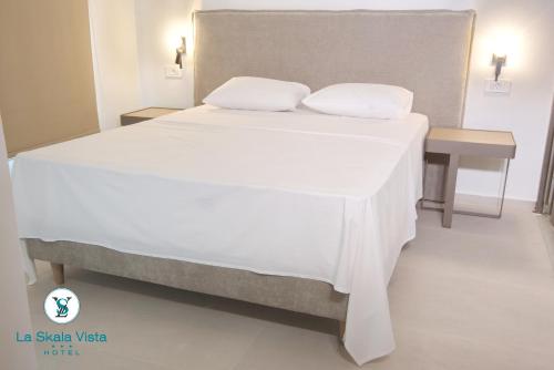 a large bed with white sheets and pillows on it at La SkalaVista in Skala Kefalonias