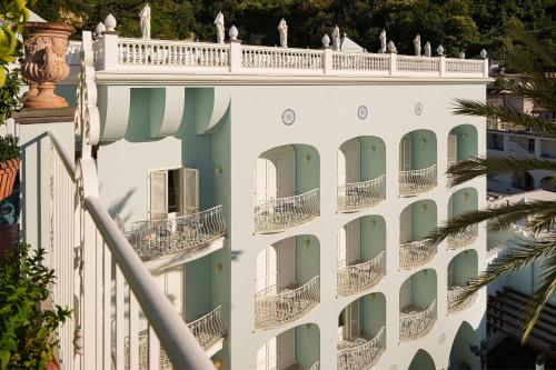 a white building with green doors and a palm tree at Manzi Hotel & Spa in Ischia