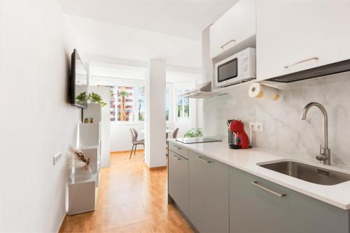 biała kuchnia ze zlewem i lodówką w obiekcie Apartamento Lucía w mieście Torre del Mar