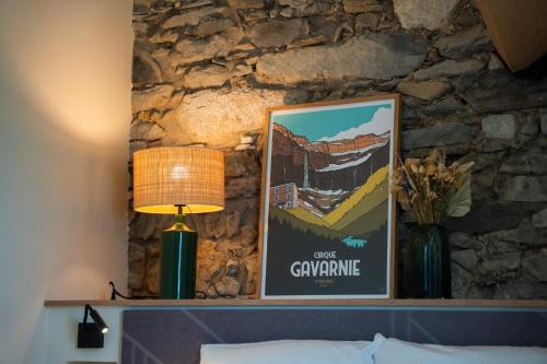 a picture on top of a bed with a lamp and a stone wall at Les Granges du Hautacam in Artalens-Souin