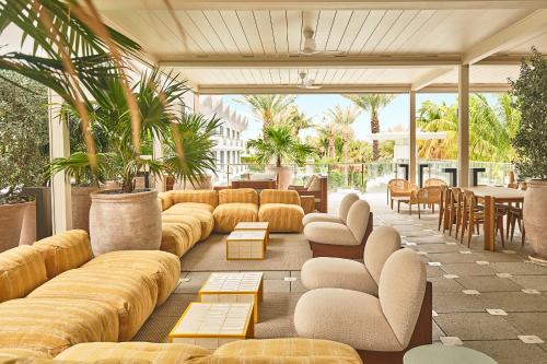 a lobby with yellow couches and tables and plants at The Shelborne by Proper, a Member of Design Hotels in Miami Beach