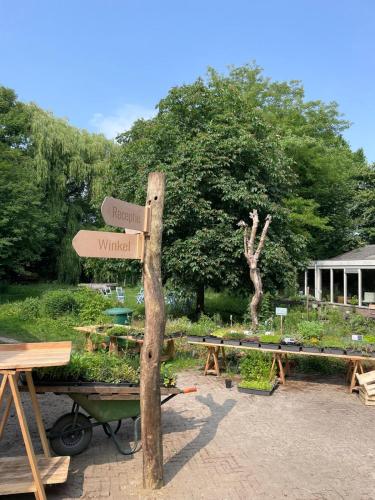 a sign for a garden with tables and a tree at Plaats De Kleine Aarde in Boxtel