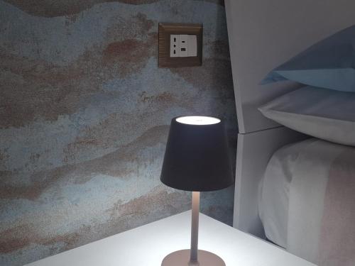 una lampada appoggiata su un tavolo accanto a un letto di Machi House a Scafati