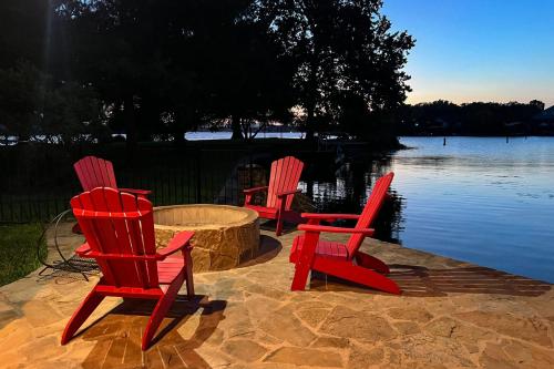 three red chairs sitting around a fire pit by the water at Paradise Cove in Granite Shoals