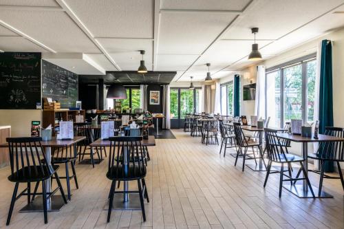 une salle à manger avec des tables, des chaises et un tableau noir dans l'établissement Campanile Vire, à Vire