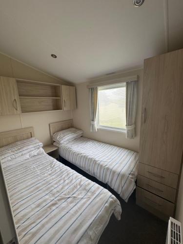 two beds in a small room with a window at Newquay Bay Resort getaway in Porth