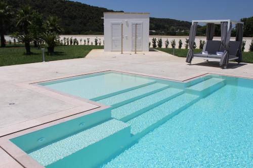 a blue swimming pool with a chair next to it at Dani's residence in Supersano