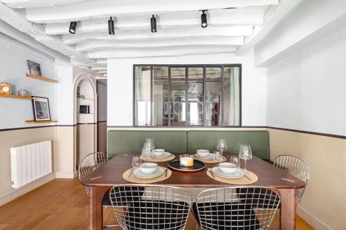 une salle à manger avec une table et des chaises en bois dans l'établissement Appartement design et confortable au cœur du Marais, à Paris