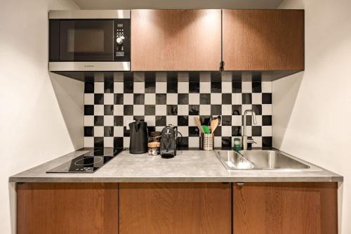 un comptoir de cuisine avec un évier et un micro-ondes dans l'établissement Appartement design et confortable au cœur du Marais, à Paris