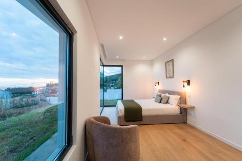 a bedroom with a bed and a large window at Auréa House - Luxury Ocean View in Feteiras