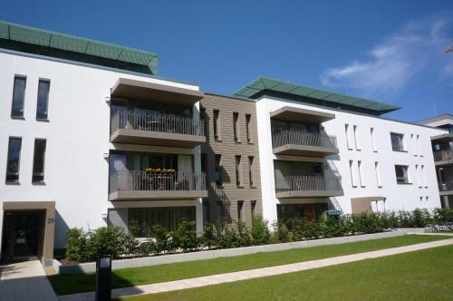 a white apartment building with balconies and a lawn at Residenz/Meeresrauschen in Warnemünde