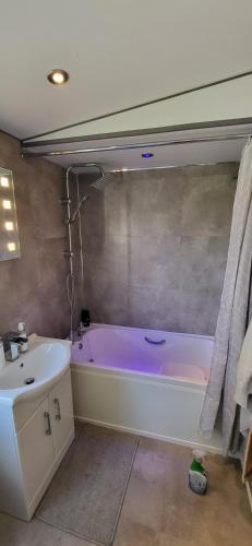 a bathroom with a purple tub and a sink at Sunny corner caravan in Saint Osyth