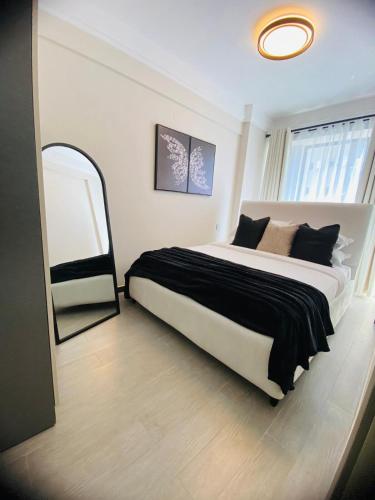 a bedroom with a large bed and a mirror at Cozy 1BR Hideout Kilimani in Nairobi