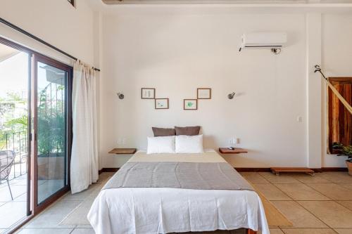 een witte slaapkamer met een bed en een balkon bij Casa Hibiscus Zaachila 2 A in Puerto Escondido