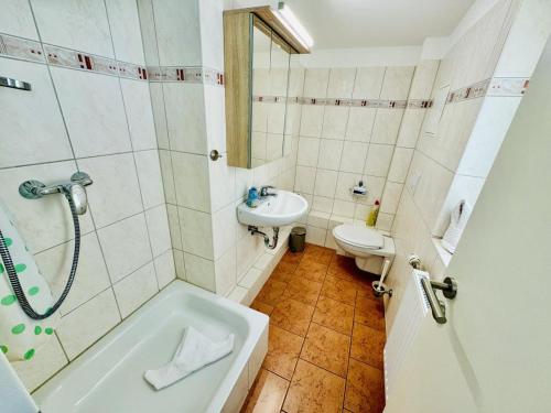 a bathroom with a sink and a tub and a toilet at Appartement Schwalbenflug in Warnemünde
