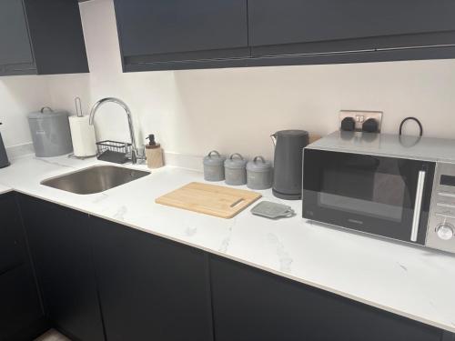 a kitchen counter with a microwave and a sink at Portbridge Nest in Chew Magna