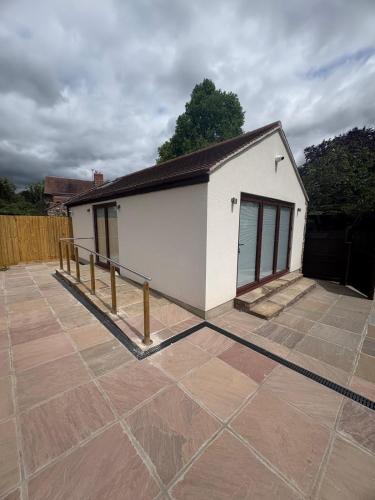 a small white building with a fence on a patio at Portbridge Nest in Chew Magna