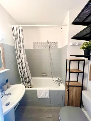 a bathroom with a tub and a toilet and a sink at L'Estival, Royan in Royan